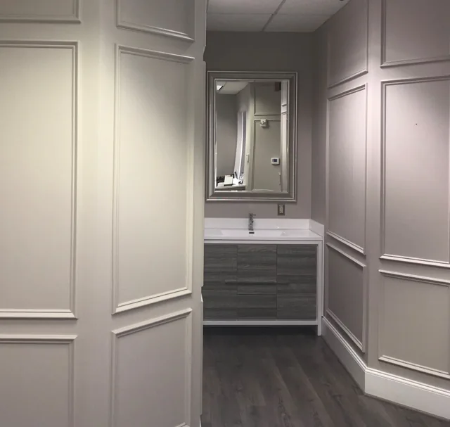 Paneled office hallway with a built-in wash station and mirror